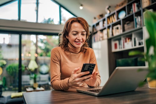 mujer sonriendo revisando su teléfono