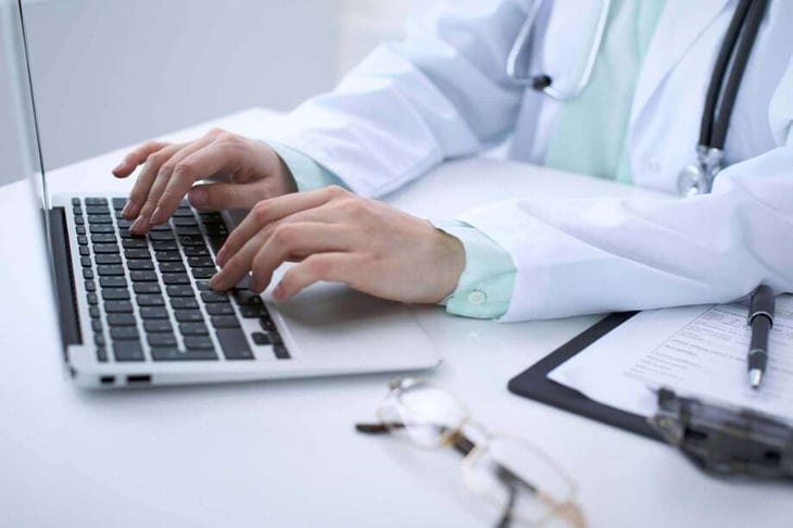 acercamiento a manos de doctora tecleando en laptop