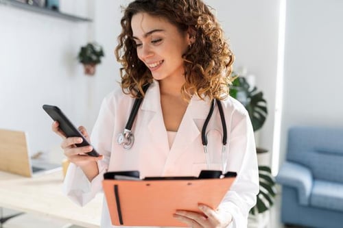 female-european-adult-doctor-consultation-room-using-phone-and-holding-folder-print-1